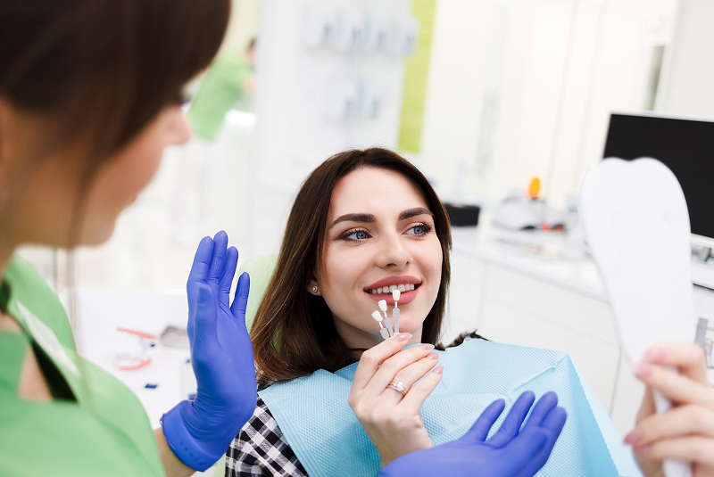 young woman looking at veneers in mirror